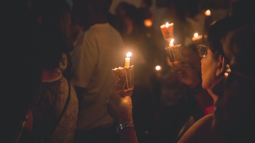 People attending mass with candles in hands