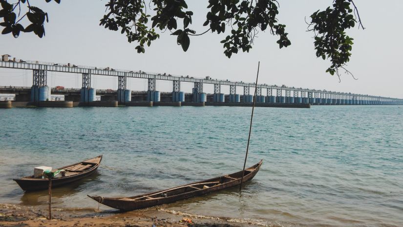 2 boats on the banks of a river with a bridge in the distance during daytime