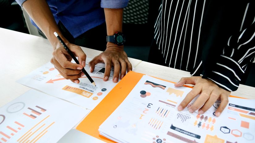 two people planning for a meeting with files and charts on a table