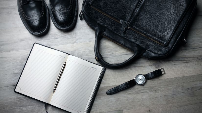 a pair of shoes, a notebook, a watch and a bag kept on the floor