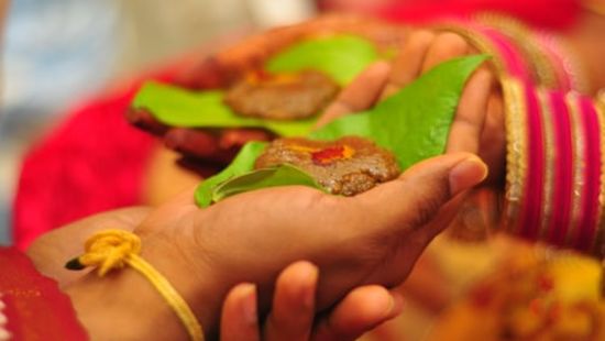 groom and bride holding beetle leaves for wedding rituals