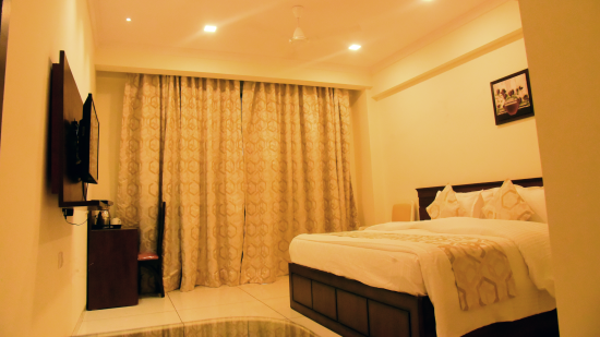 A side view of a bedroom shows the off-white interiors and the TV on the wall - VITS ExcellenSea, Dapoli