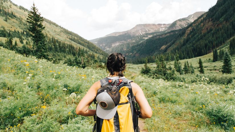 A person going hiking on a trail with mountains in the background