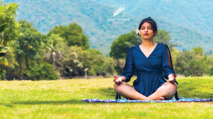 a woman sitting in the garden practising yoga - Black Thunder, Coimbatore