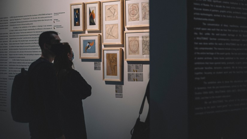 Two people looking at paintings at an exhibition