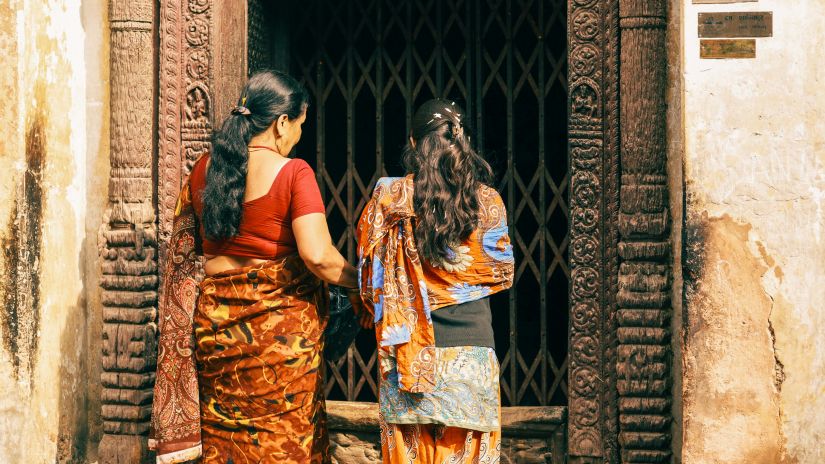 a over the shoulder shot of two women entering the temple