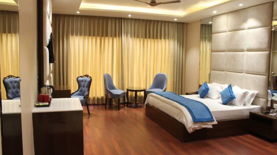 View of Deluxe room with bed and bedside tables seating area with windows and curtains  - Mastiff Hotel, Dalhousie