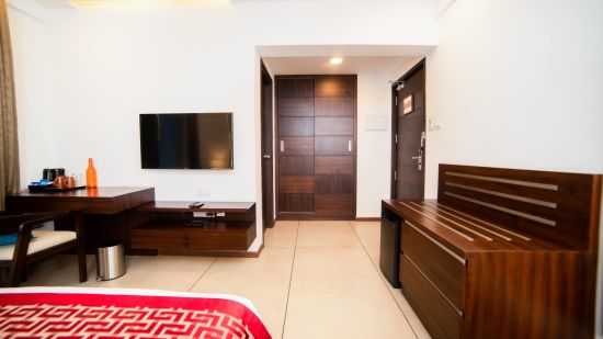 A perspective from the bedside looking towards the door in a bedroom with a television and furnishings | The Terrace Business Hotel