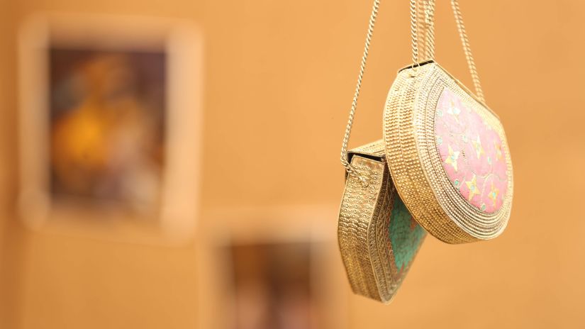 A handcrafted bag hanging from the ceiling against orange background