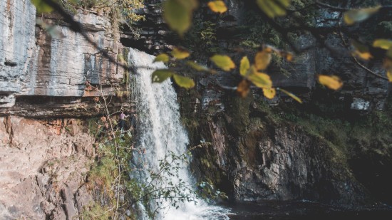 A waterfall being collected into a small pond below with rocks surrounding it