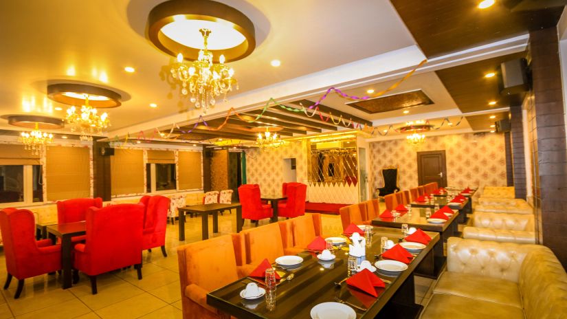 A restaurant with vibrant lights and several tables and chairs - Little Matiff Dharamshala