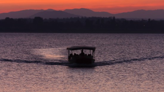 a view of sunset with a boat sailing on the river