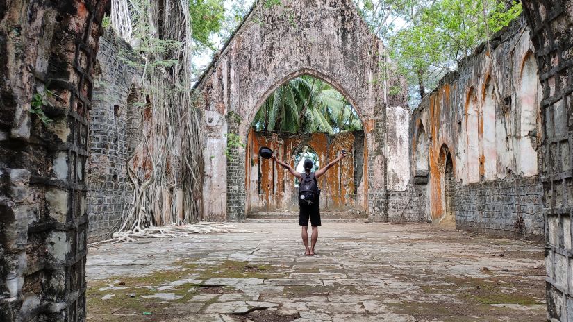 a person raising their arms in the ruins of a church