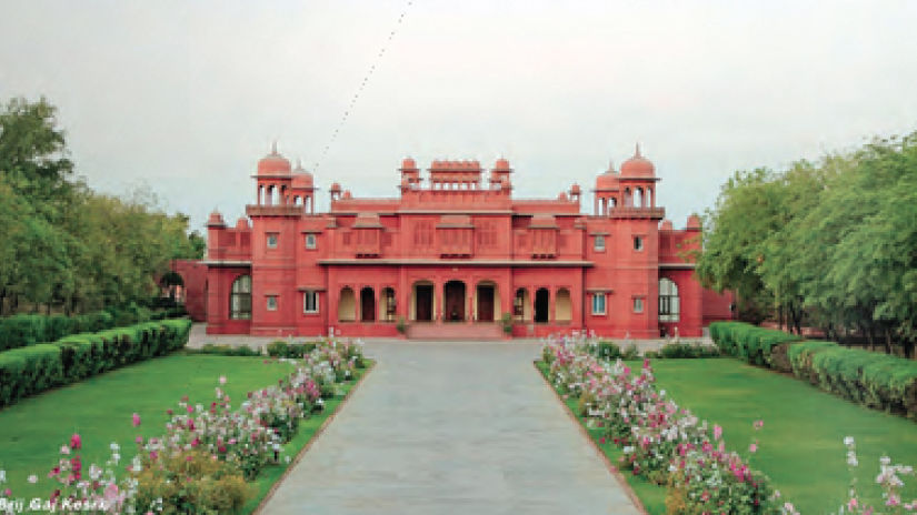 Brij Hotels - Image of a red coloured fort with a path way backed with trees on either sides