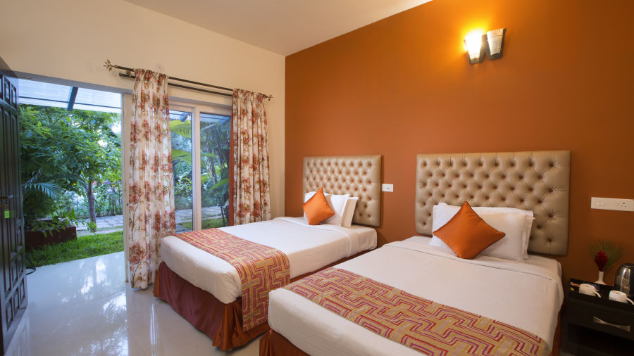 Another look at an inviting hotel room at Kairos, Yelagiri, with a white tufted headboard, orange accents, floral curtains and a view  - Kairos, Yelagiri