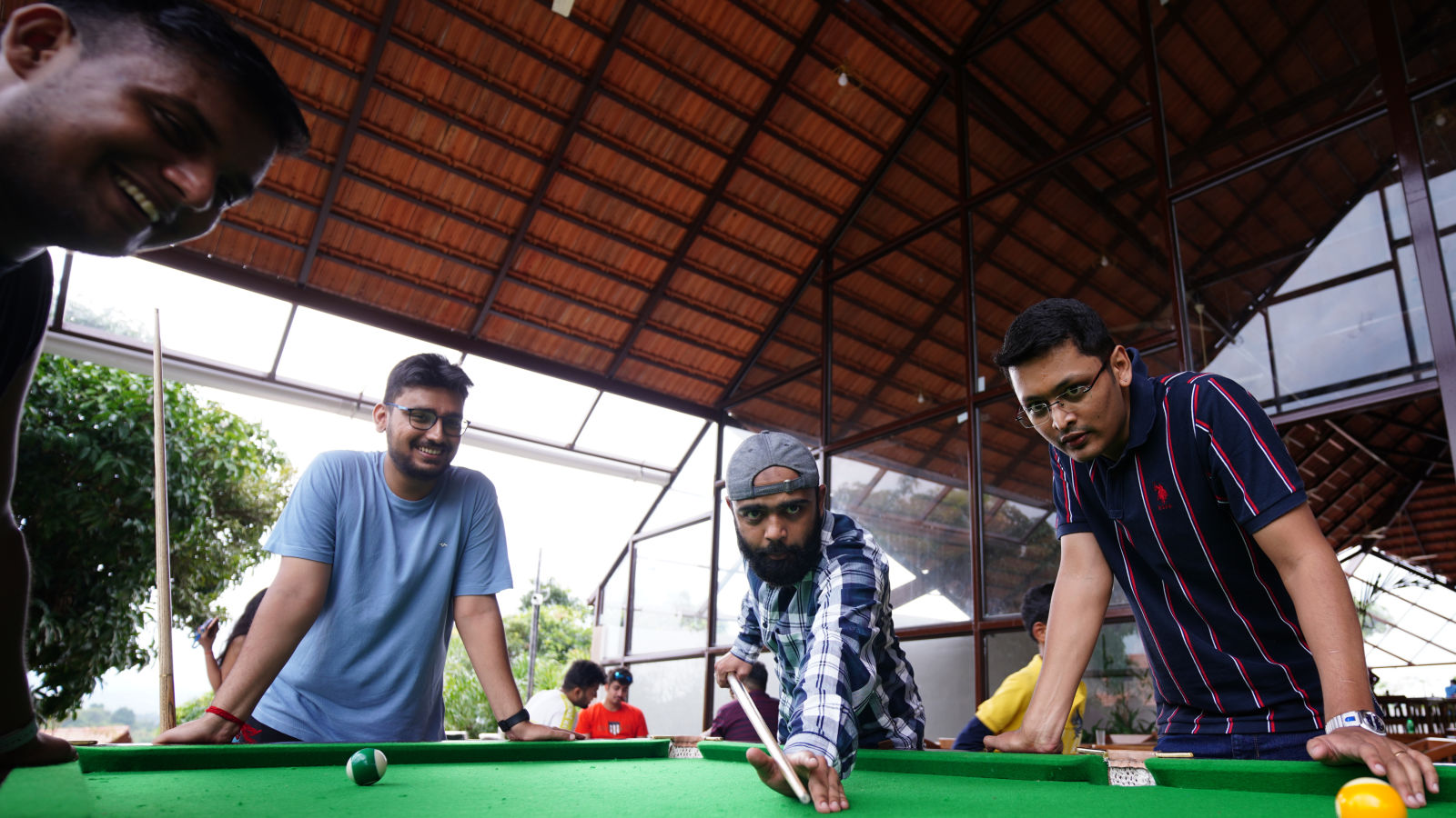 Ravishing Retreat Ramanagara - Guests focused on a game of pool with one person making the shot