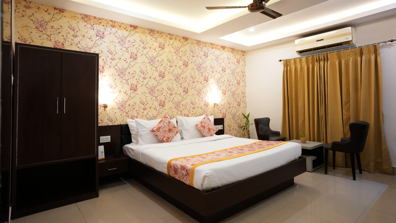 A king size bed, two chairs and a cupboard in the Premium Room at Voyage Premier Inn, Siliguri 1