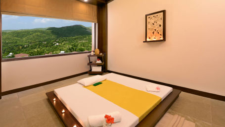 A bed on the floor with a window view of the garden inside a room at the spa - ananta udaipur