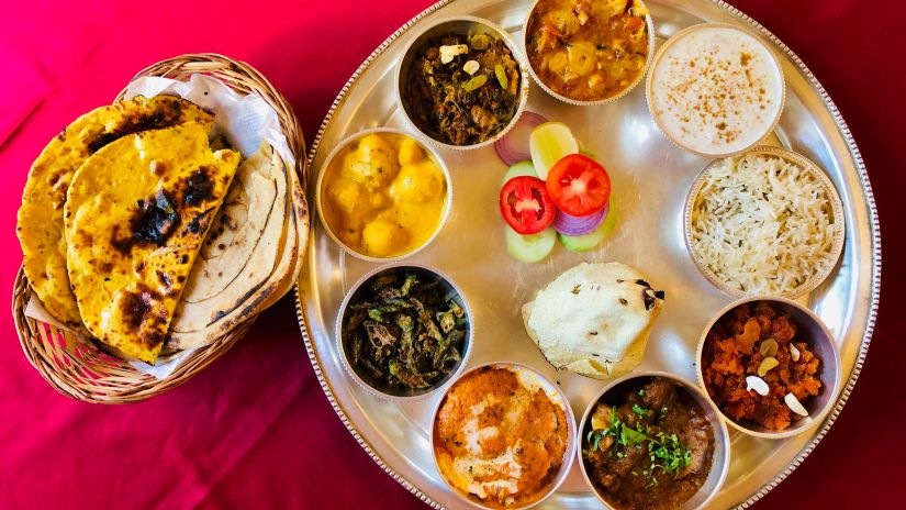 a plate of rajasthani food that includes rice, curries and bajra bread