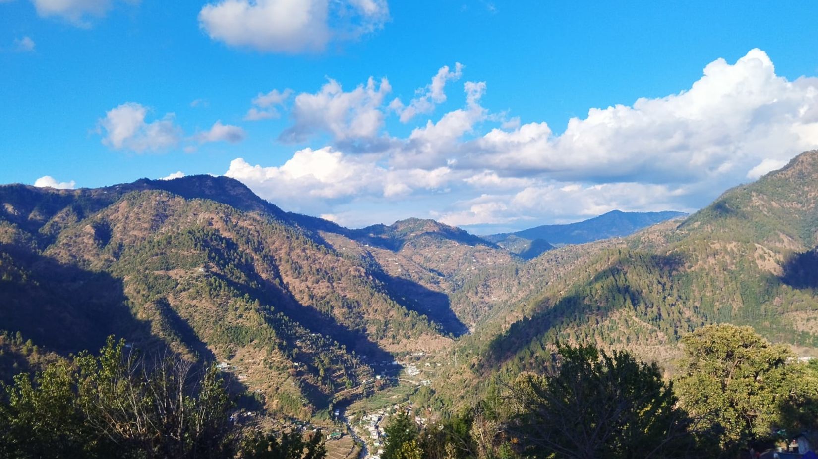 View of lush mountains with a blue sky with could scattered around