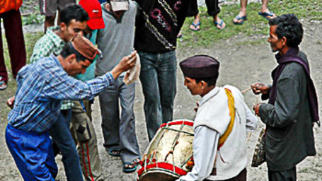 An image of musicians playing the drum and a group of men dancing during Wedding celebration