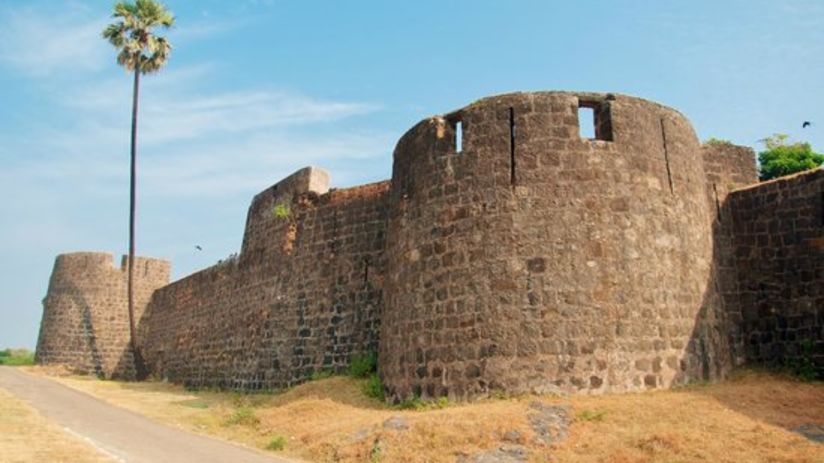 an far out view of Madh Fort with a small road on the side and blue sky in the background