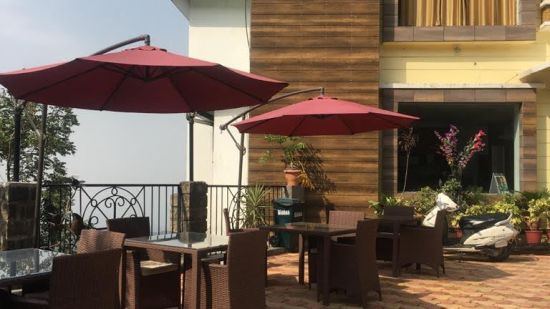 facade of Little Mastiff, Dharamshala with two red parasol placed in front of it