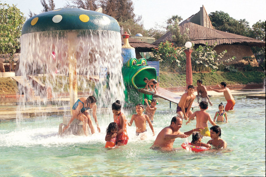 alt-text Water Kingdom - a group of children with their parents playing in a pool during daytime