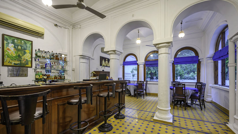 Various bar stools in front of a bar table with drinks in the background - The Baradari Palace