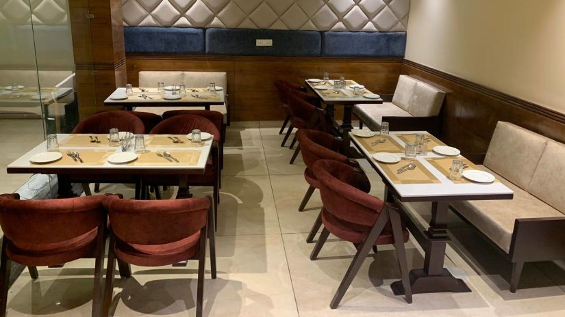 The Mastiff Hotel in Dalhousie showcases stylish interior design with tables arranged in a Tangelo theme as seen from a side perspective -  Mastiff Hotel, Dalhousie