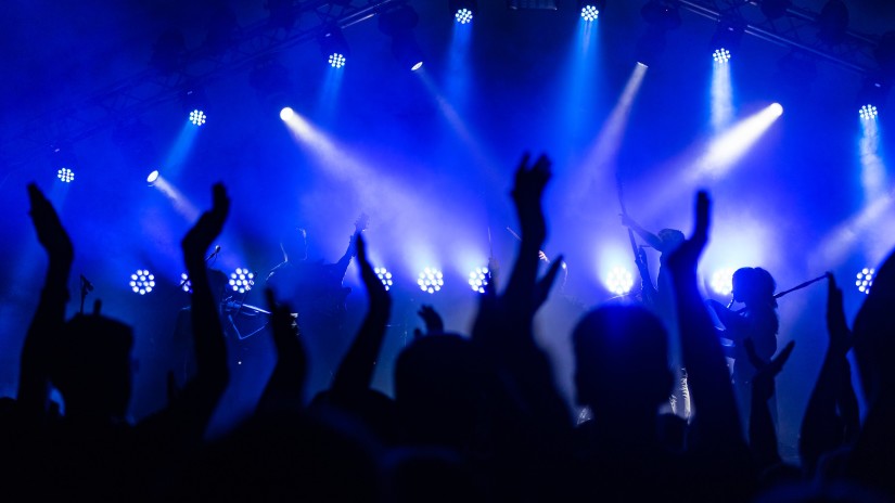 A close shot of people in a room of saturated lights puttings hands up and dancing