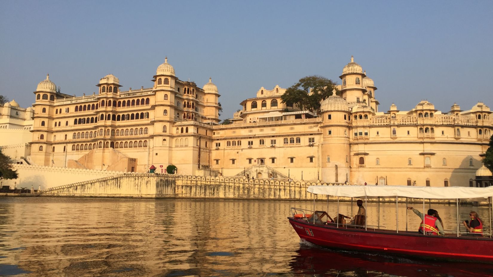 the mesmerizing panorama of City Palace, Udaipur, and the tranquil lake from the top-rated business hotel in Udaipur.- Udaipur