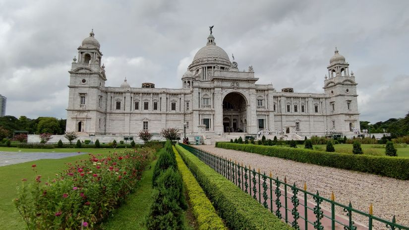 a view of Victoria memorial from afar with the grass area on either side and a walkway leading to the memorial