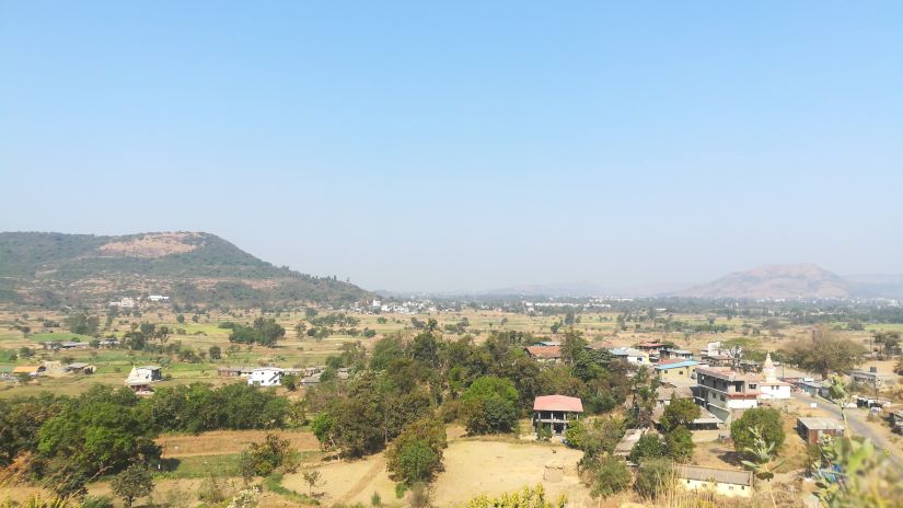 an overview of Maval village with a small hill and blue sky in the background