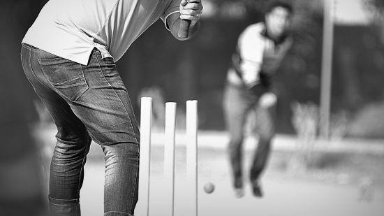 Two people playing cricket on a cricket pitch