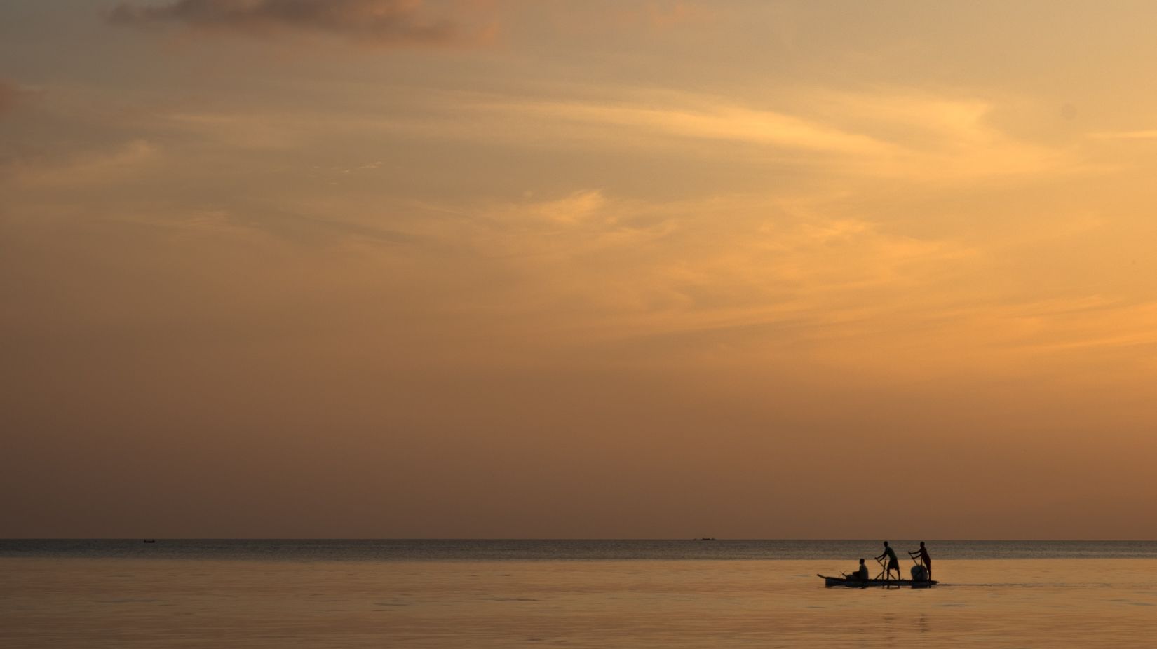 two people in a boat with the evening sky in the background