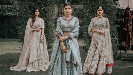 three women posing wearing bridal lehengas