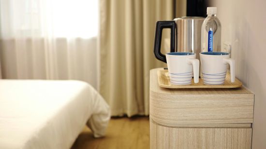 A table with an electric kettle and mugs inside a hotel room