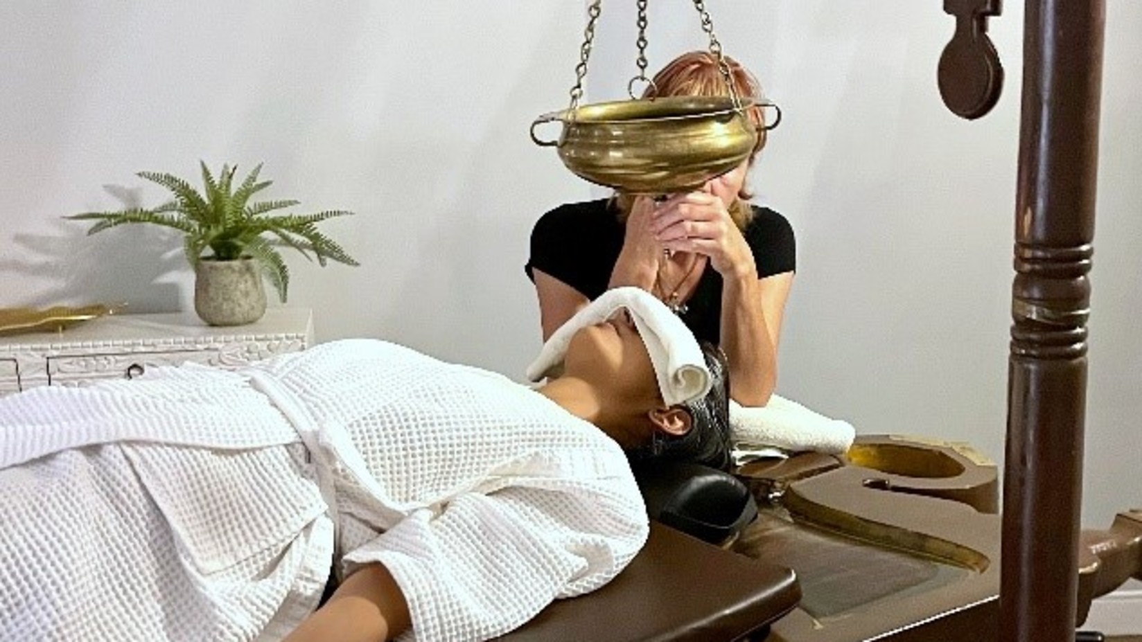 A woman lying down on a table receiving Ayurvedic therapy