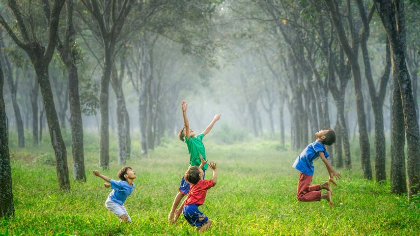 children playing in the park by jumping with trees in the background