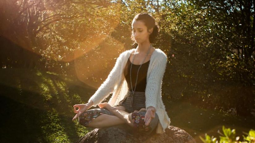 Image of a lady sitting in a garden doing meditation