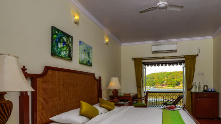 A double bed with painting hung above and balcony in the centre inside coral room at neemrana s three waters