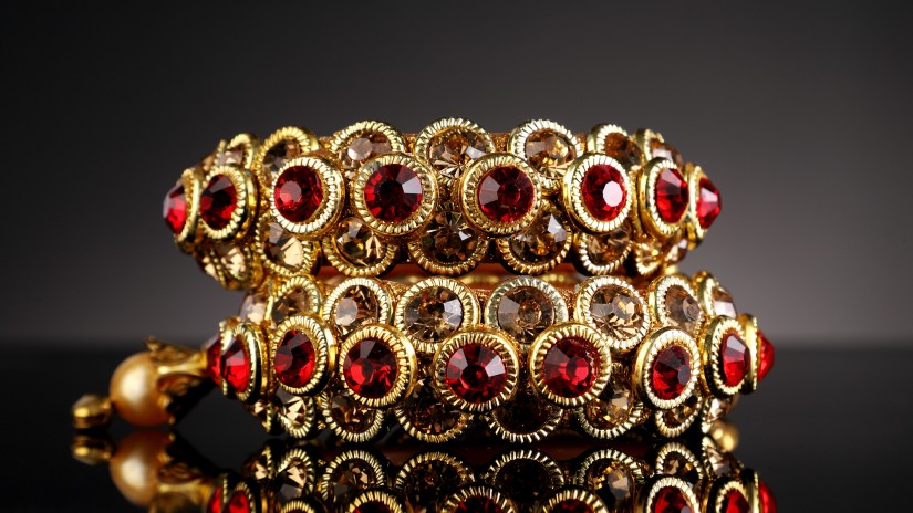 a close up image of a intricately made gold jewellery with rubies