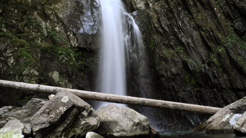 Small waterfall in between rocks flowing down to a pool of water