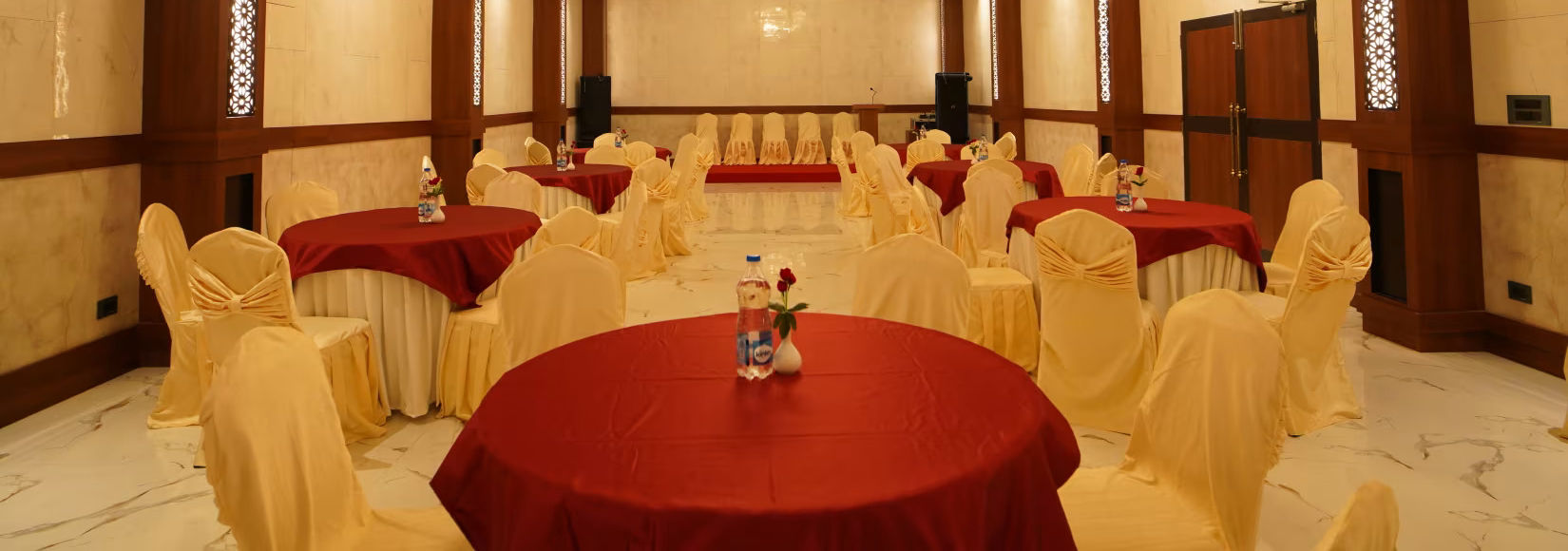 overview of the banquet hall with round table seating arrangement and a chandelier hung above - Shanti Seaview Resort & Spa