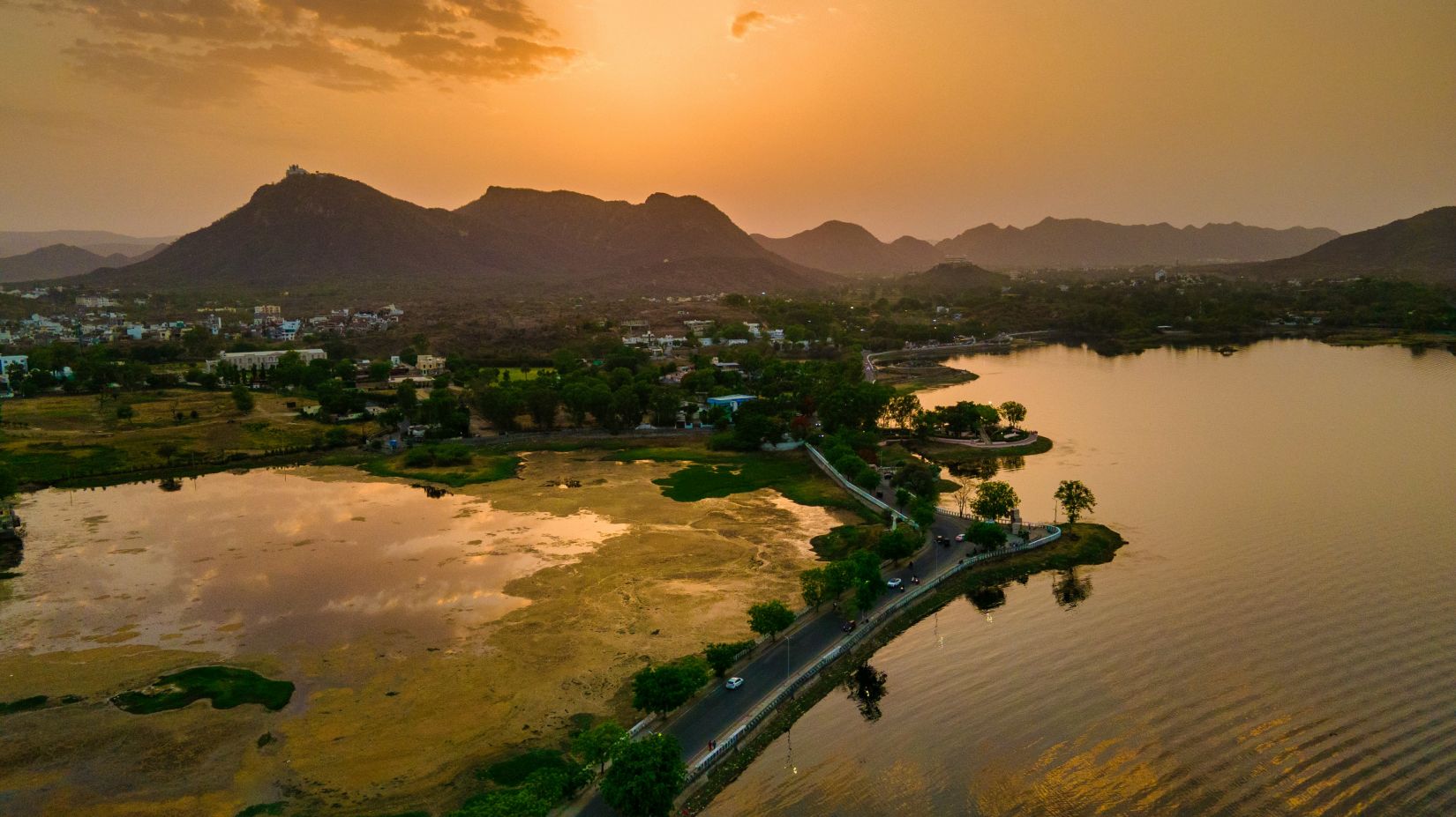 an overview of Fateh Sagar Lake in udaipur with the sun in the background