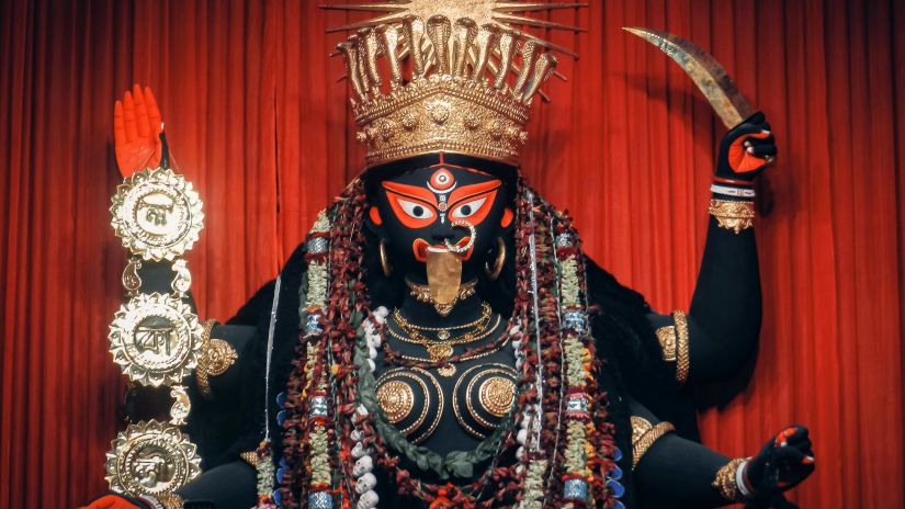 Statue of Kali devi decorated and with a red background 