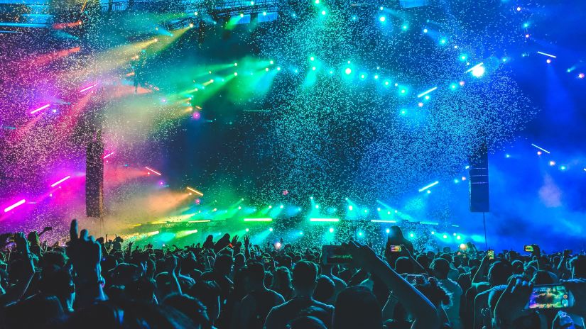 a crowd of people dancing and celebrating with strobe lights in the background and bubbles floating