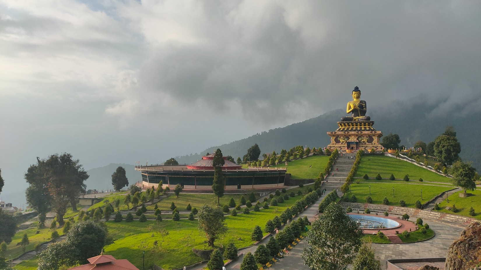 an image of a hill with trees and buildings in the distance