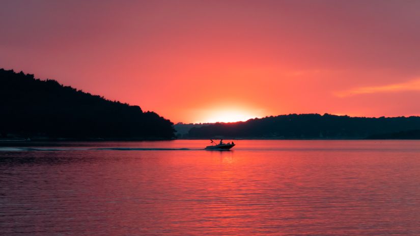 a boat ride during sunset with mountains in the background offering hues of pink